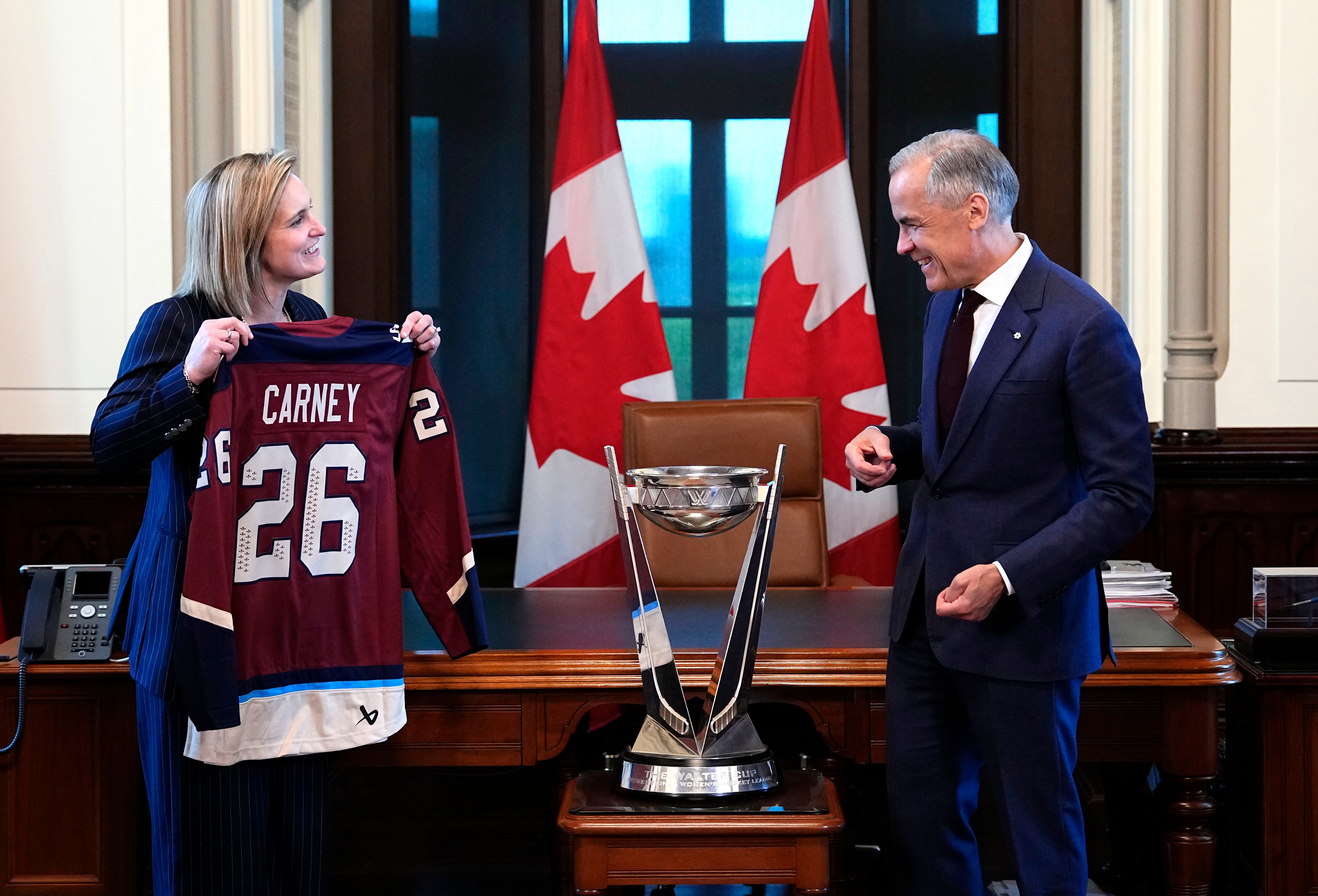 Montreal Victoire captain Marie-Philip Poulin presents Canada's Prime Minister Mark Carney with a custom Victoire jersey, as the team brings the Walter Cup PWHL championship trophy to his office on Parliament Hill in Ottawa, Ontario, Tuesday, June 2, 2026.
