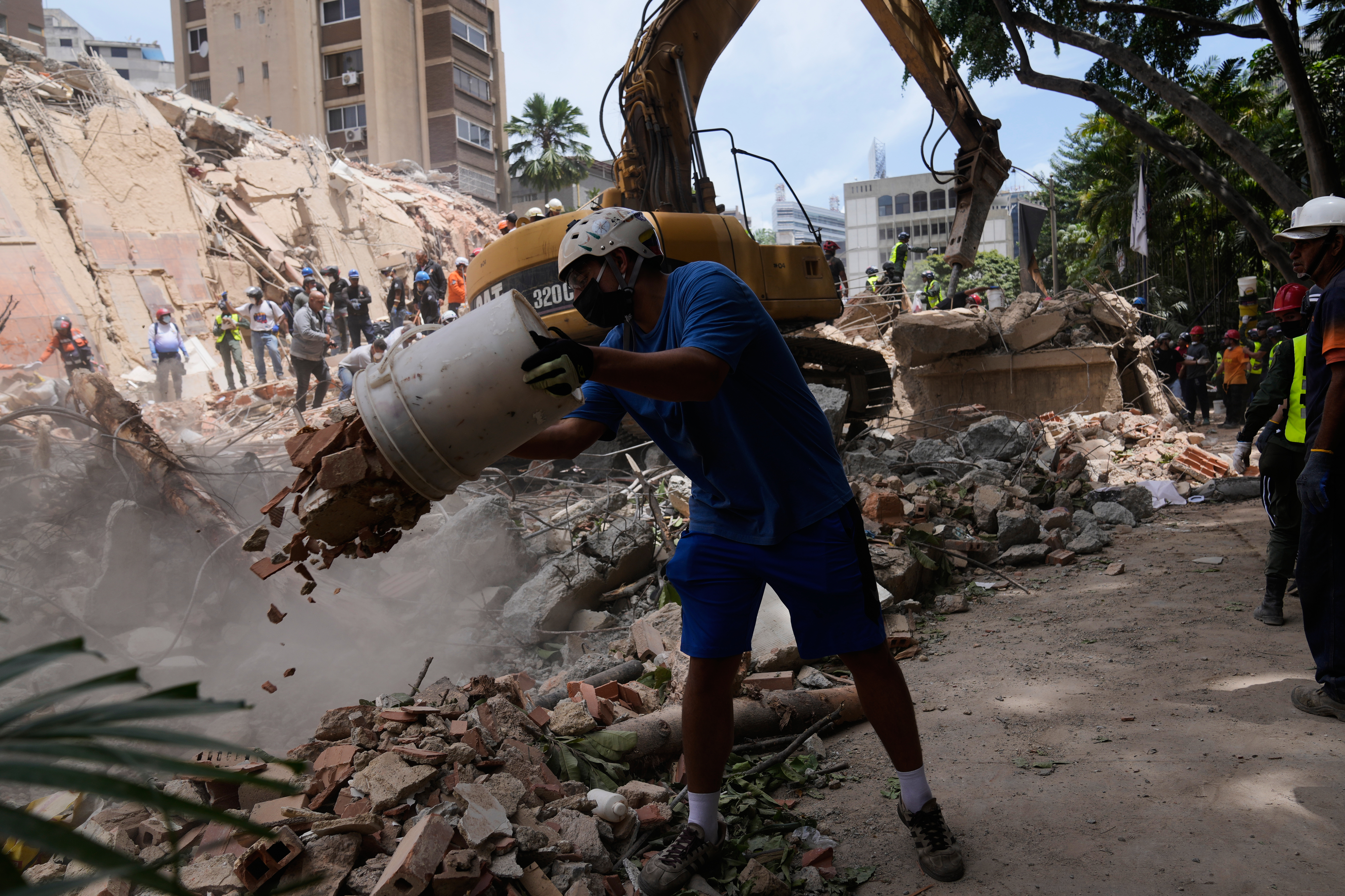 Residents help to remove rubble from a collapsed building in Caracas, Venezuela, Thursday, a day after successive powerful earthquakes struck the country. Over 230 people have been killed so far.