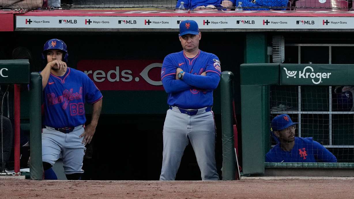 New York Mets manager Carlos Mendoza center, looks out from the dugout during the fourth inning of a baseball game against the Cincinnati Reds in Cincinnati, Monday, June 15, 2026.