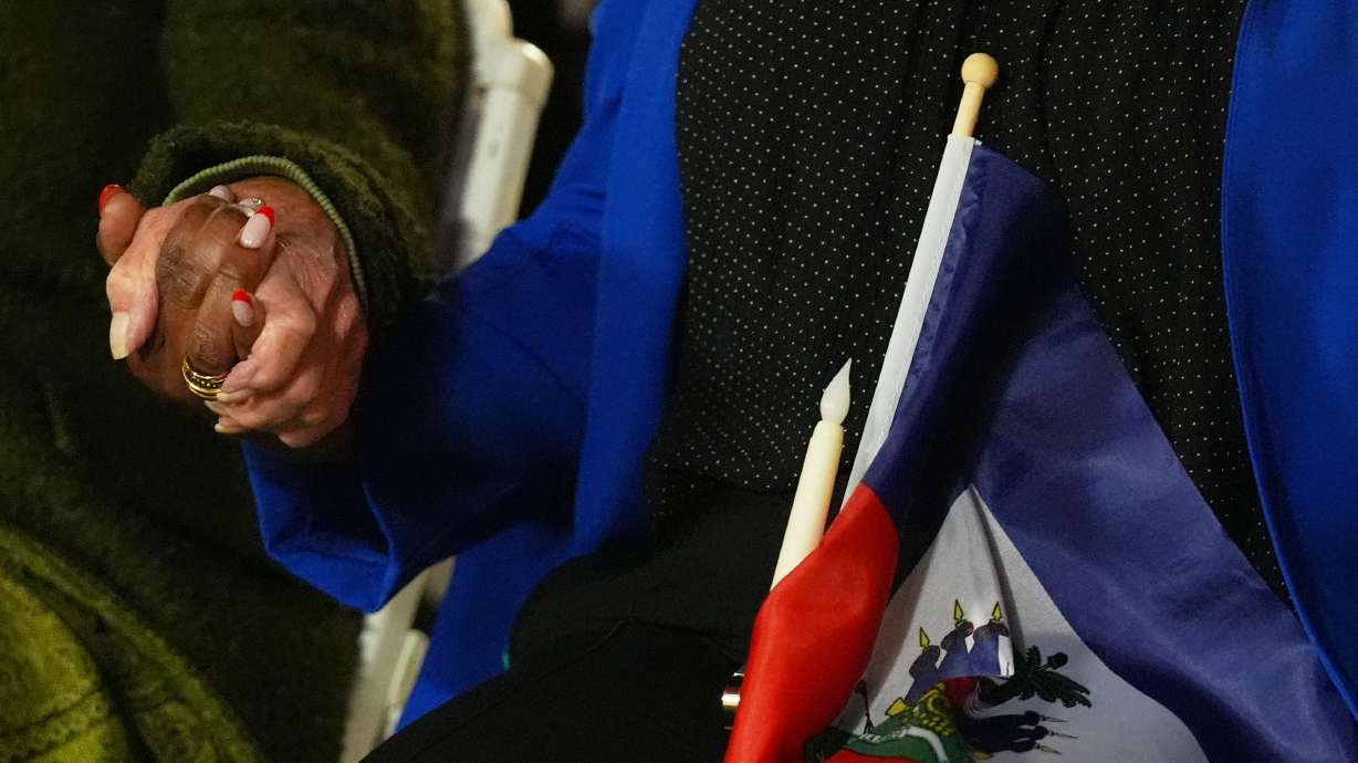 People hold hands and a Haitian flag during a vigil at the Little Haiti Cultural Complex after a federal judge blocked the Trump administration from ending temporary immigration status, or TPS, for Haitians, Feb. 3, in North Miami.