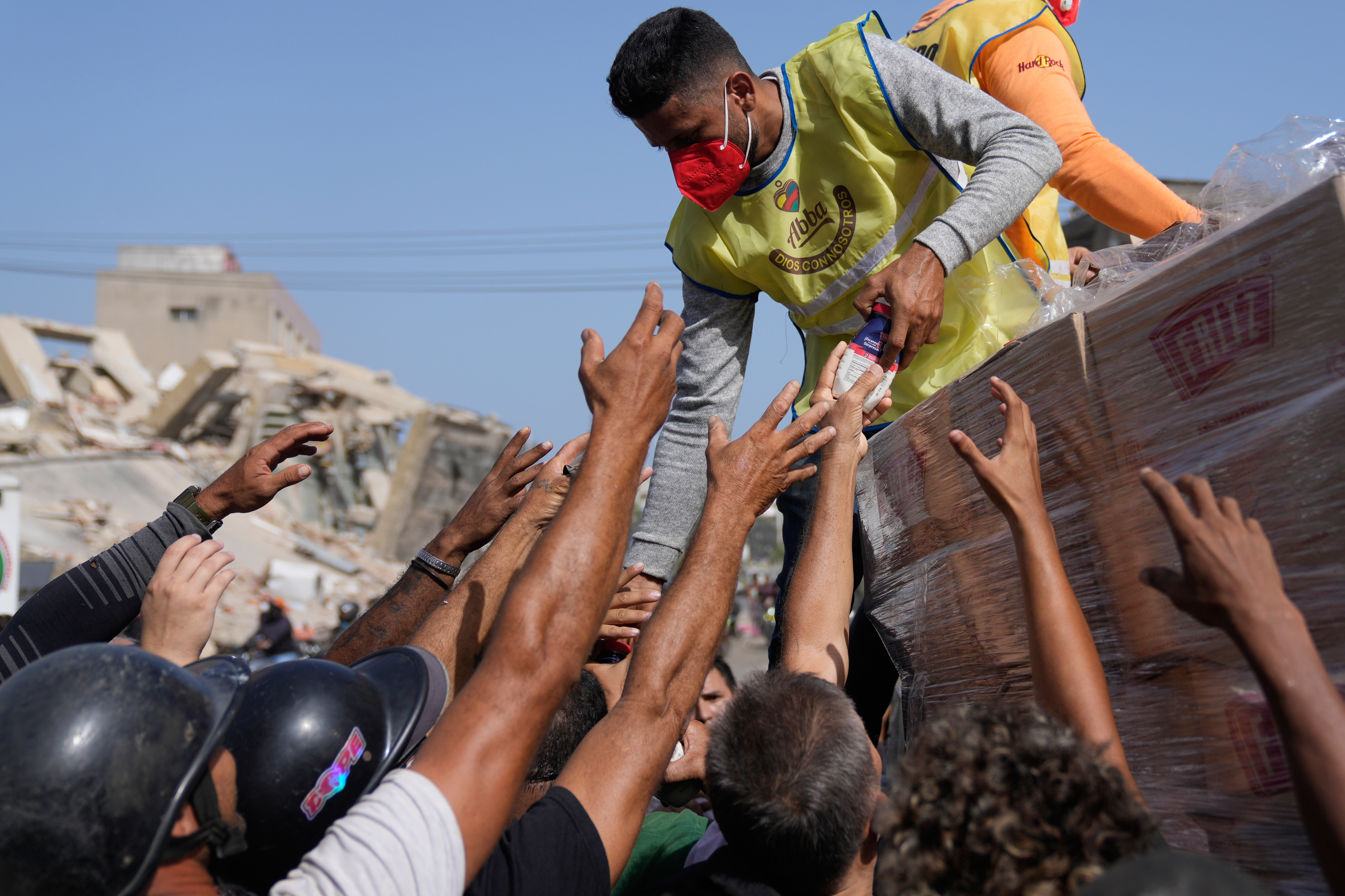 Members of a religious organization distribute food to people affected two days after an earthquake struck La Guaira, Venezuela, Friday. People are taking the search for the missing into their own hands.