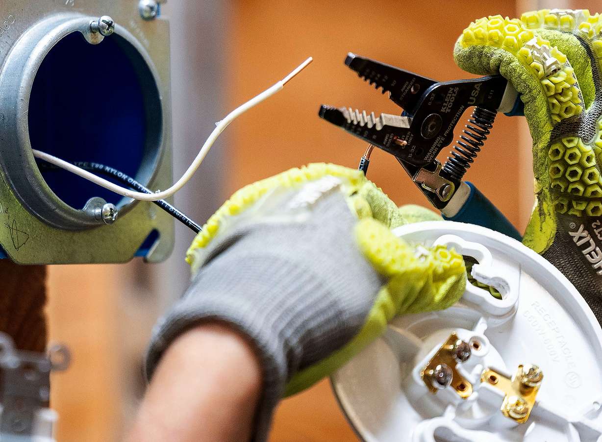 Kinzie Taylor practices wiring three-way switches at the Utah Technical Training Alliance in West Jordan on Friday. Rep. Burgess Owens touted the need for more "earn and learn" education models.