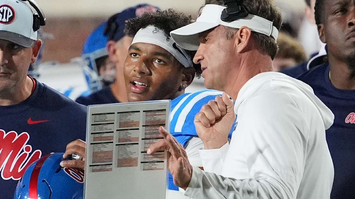 FILE - Mississippi head coach Lane Kiffin, center right, confers with quarterback Trinidad Chambliss, center left, during an NCAA college football game against Florida, Nov. 15, 2025, in Oxford, Miss.