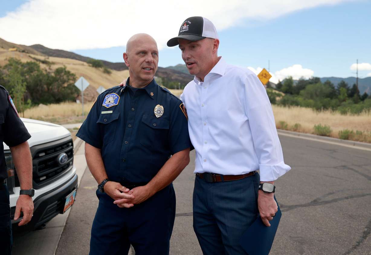 Salt Lake City Fire Chief Karl Lieb and Gov. Spencer Cox talk after a press conference about current wildfire conditions with the Bonneville Fire burn scar in the background in Salt Lake City on Thursday, June 25, 2026.