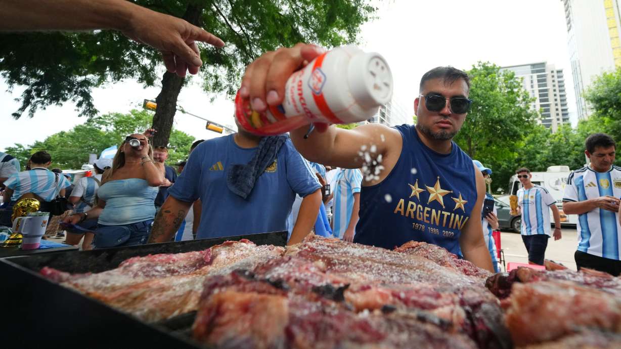 Lucas Martinez, of Dallas, an Argentina supporter, seasons meat with salt while grilling during a rally ahead of their team's World Cup Group J soccer match against Austria, Sunday, June 21, 2026, in Dallas.