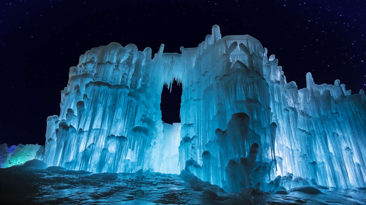 A massive ice sculpture is illuminated with a very starry night sky in the background. (AJ Mellor, Ice Castles)