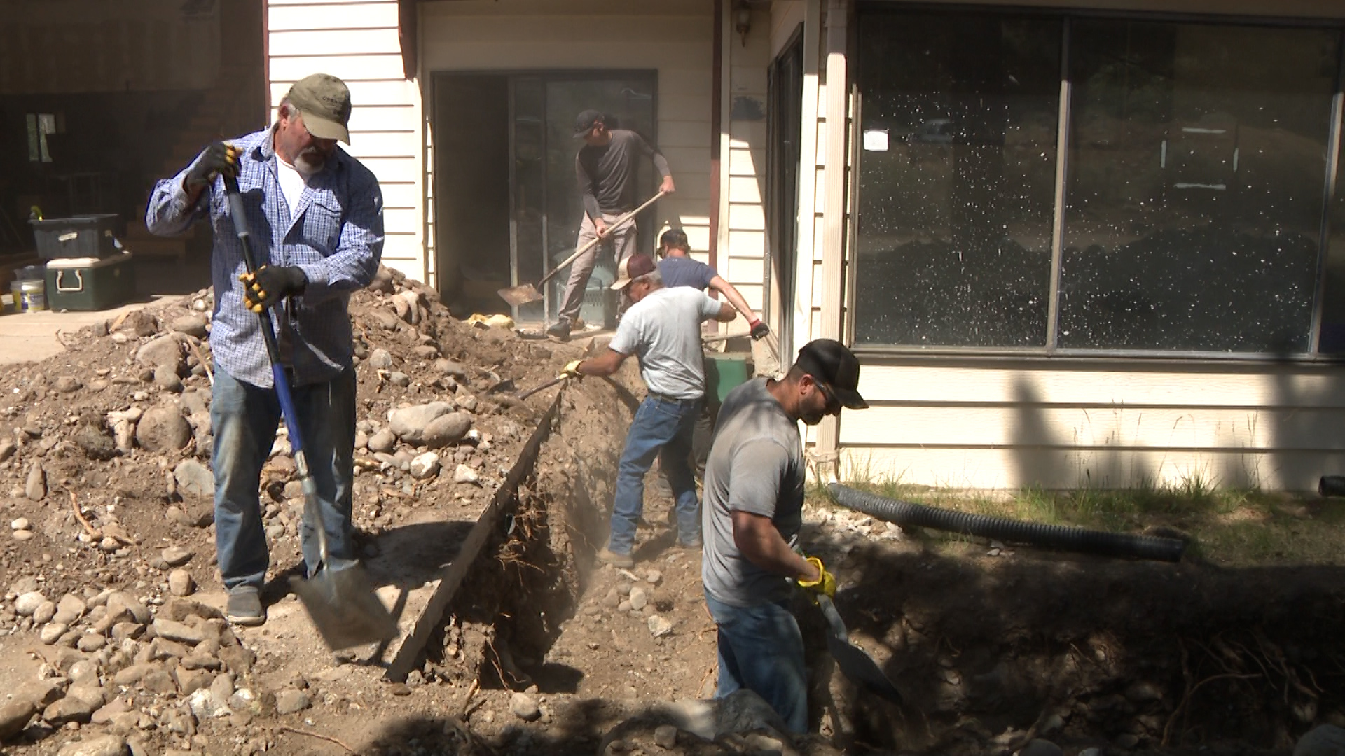 Volunteers help cover a water main at Larsen's home Saturday.