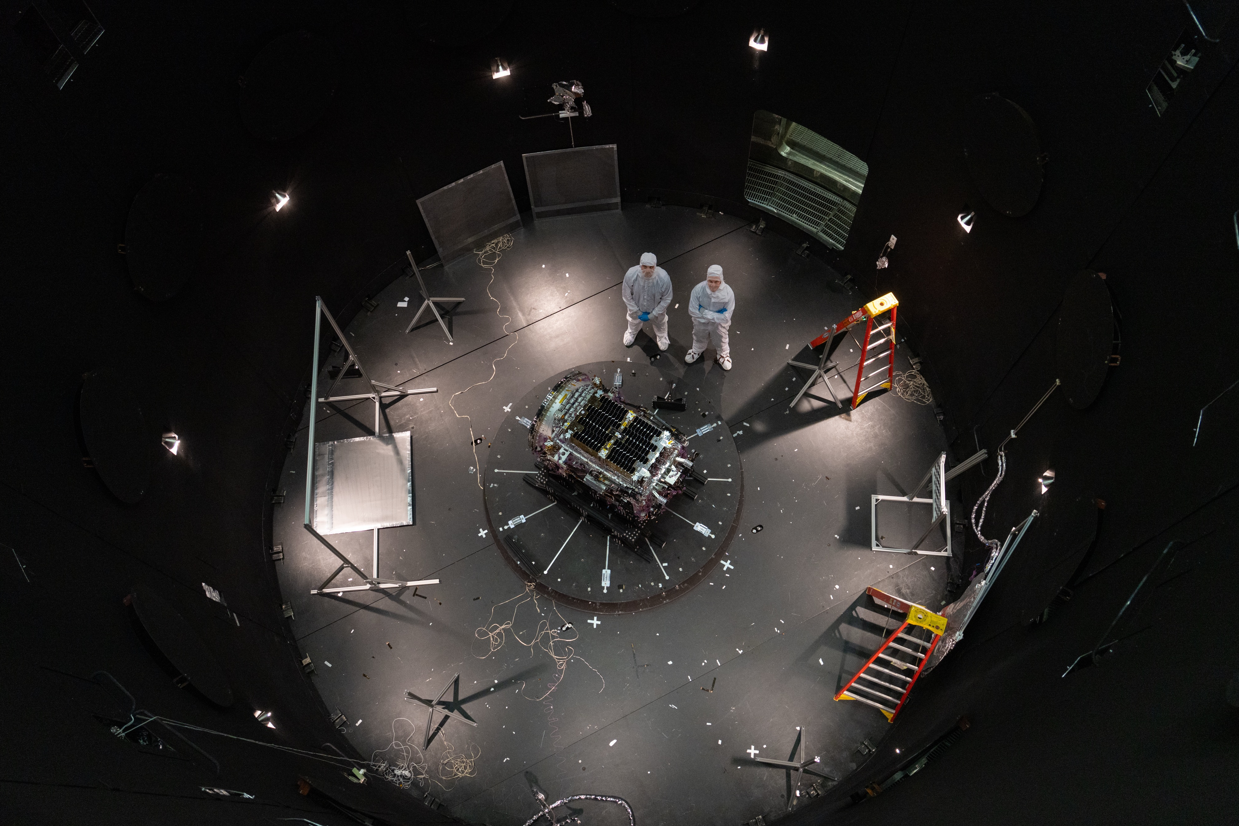This photo provided by NASA shows Kieran Wilson, LINK’s principal investigator, and Hunter Robertson, a space systems engineer, both at Katalyst Space, standing next to their spacecraft inside the SES (Space Environment Simulator) at NASA’s Goddard Space Flight Center in Greenbelt, Md., April 17, ahead of thermal vacuum testing.