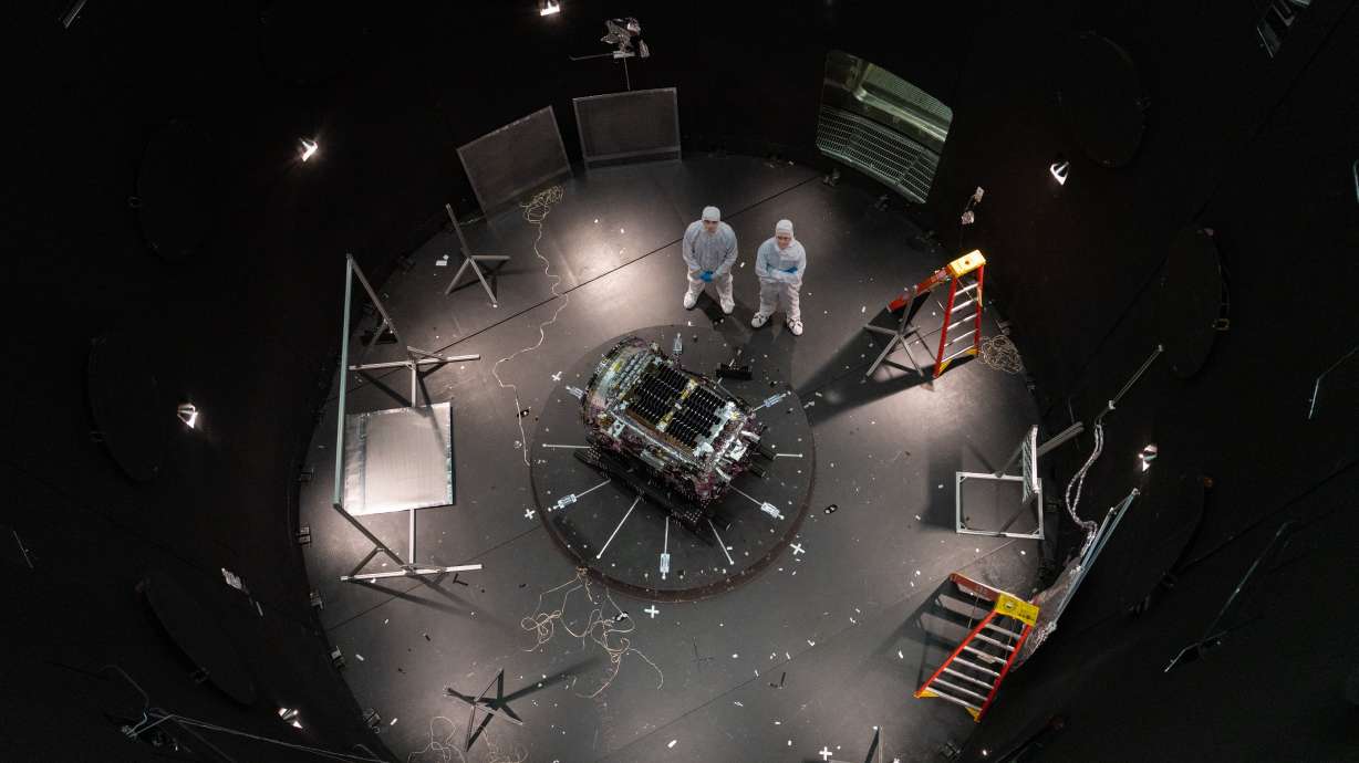 This photo provided by NASA shows Kieran Wilson, LINK’s principal investigator, and Hunter Robertson, a space systems engineer, both at Katalyst Space, standing next to their spacecraft inside the SES (Space Environment Simulator) at NASA’s Goddard Space Flight Center in Greenbelt, Md., April 17, ahead of thermal vacuum testing.