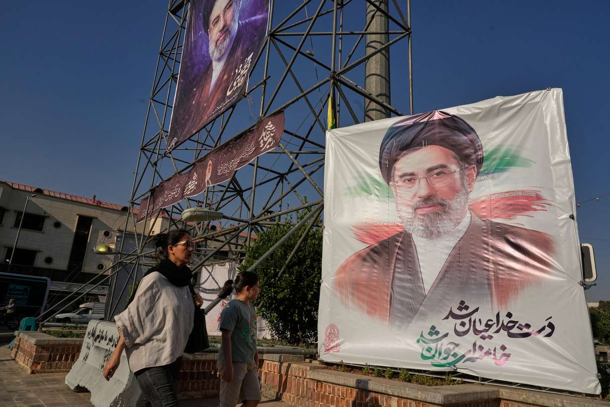 People walk past banners featuring portraits of the Iranian Supreme Leader, Ayatollah Mojtaba Khamenei, in downtown Tehran, June 29. Remarks attributed to Khamenei on Saturday warned of "unforgettable lessons" for the U.S. if the trading of airstrikes continues.