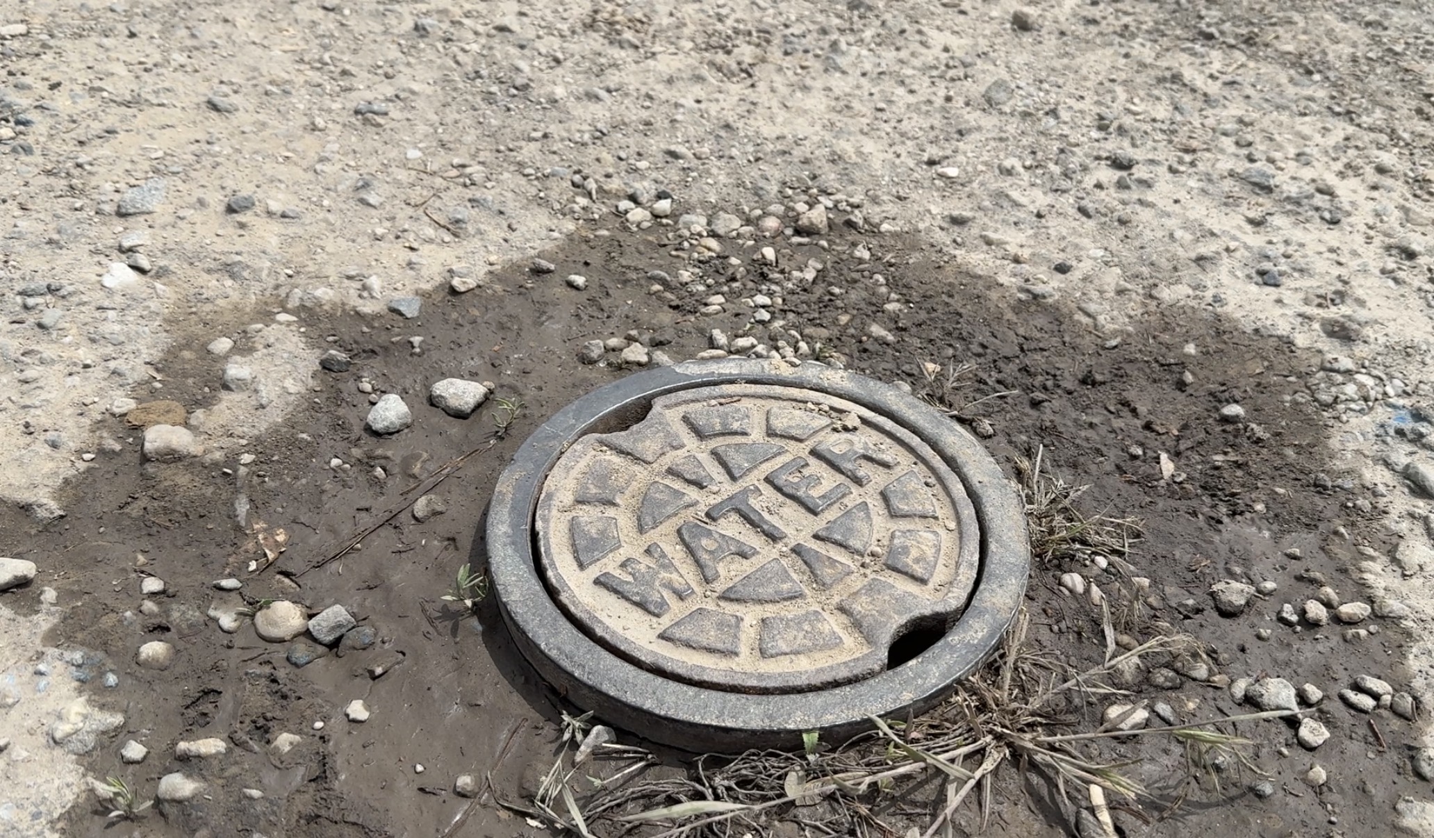 A water cover sits in mud and gravel in an Ogden neighborhood where residents learned they may be responsible for private pipes once tied to an HOA.