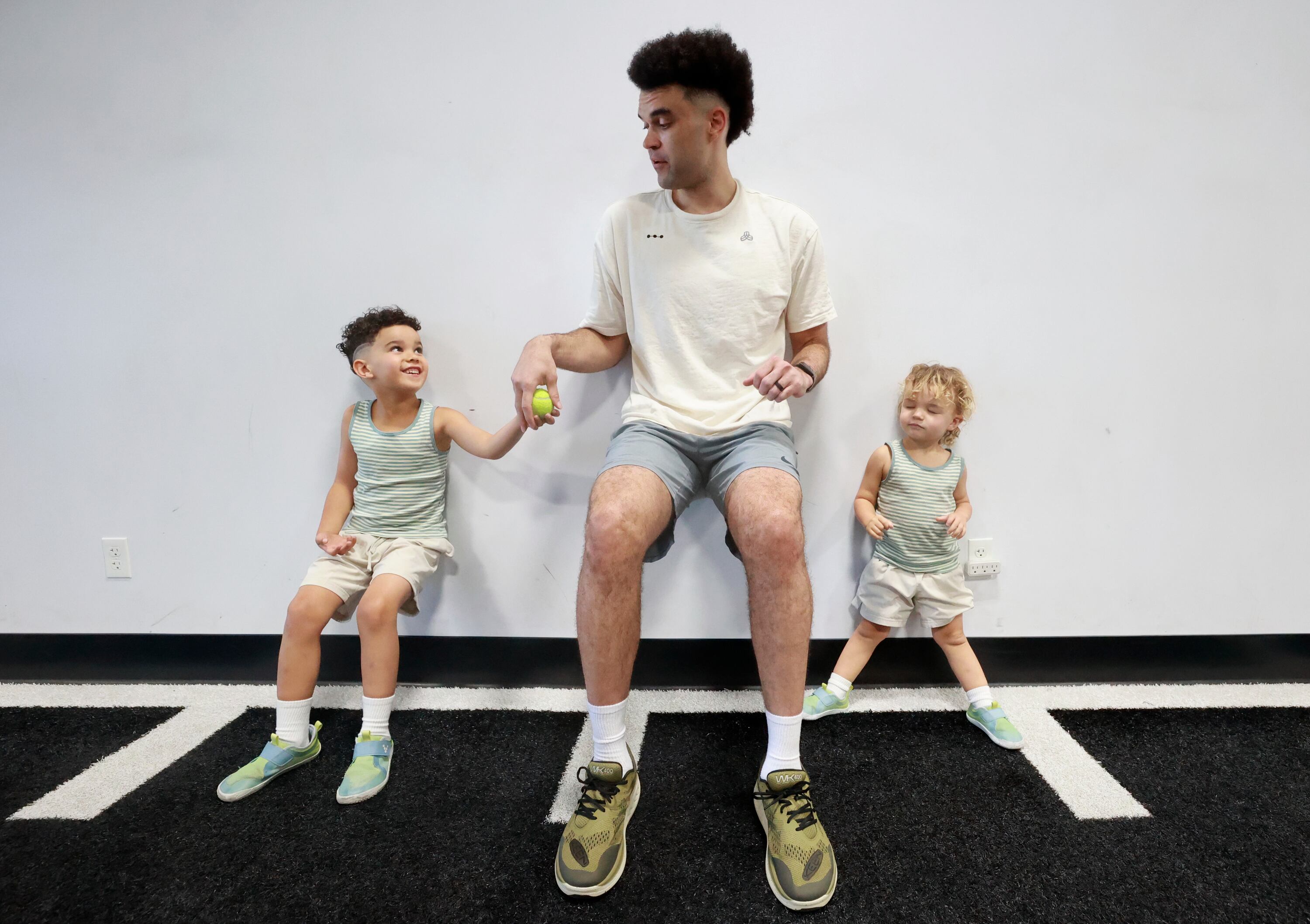 Elijah Bryant, former BYU basketball player, passes a ball between his sons Blu, left, and Rocco, right, while doing wall sits at Raven Performance Therapy in American Fork on June 25. Bryant currently plays for Hapoel Tel Aviv of the Israeli Ligat HaAl and the EuroLeague but is in Utah for the offseason.