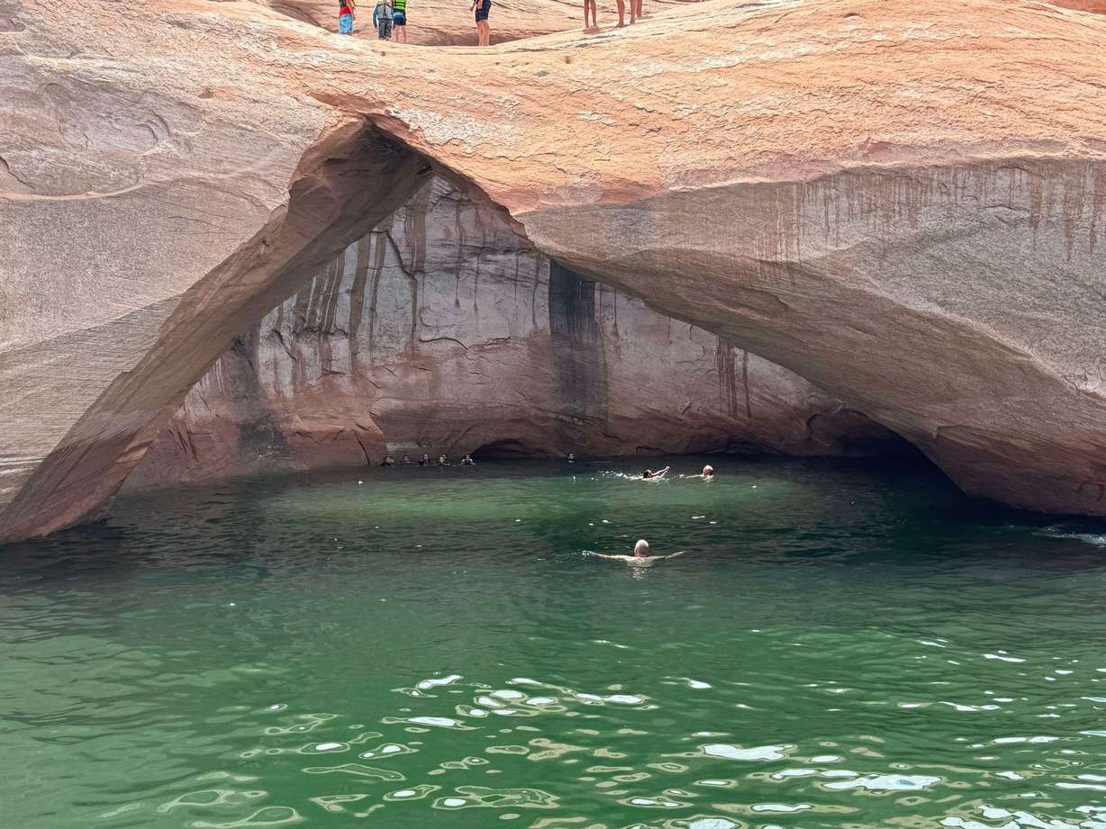 Swimmers explore the cove behind Toilet Bowl arch on Lake Powell. (Greg Sanders)