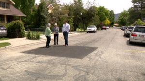 Homeowners Carole Edison and Ann Garret show Matt Gephardt where crews had to cut open the street to reach where her damaged sewer line met the main line. (Stuart Johnson, KSL TV)