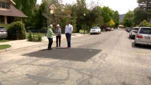 Homeowners Carole Edison and Ann Garret show Matt Gephardt where crews had to cut open the street to reach where her damaged sewer line met the main line. (Stuart Johnson, KSL TV)