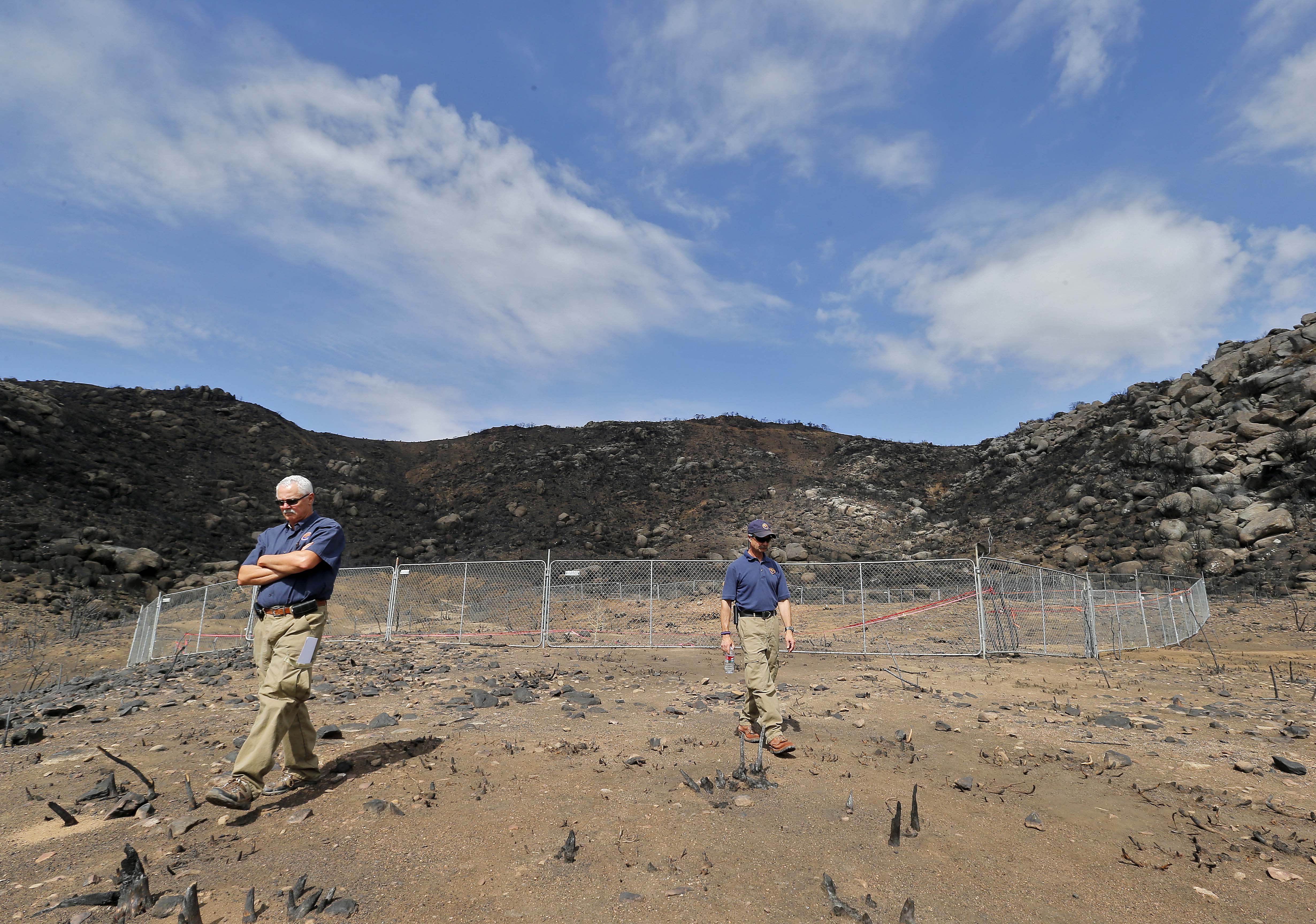 Jerald Payne, left, and Kevin Boness stand at the site where 19 firefighters died battling an Arizona wildfire, July 23, 2013, in Yarnell, Ariz. As the fire grew out of control, the firefighters quickly worked to clear the area of scrub and brush hoping to endure the intense heat in their emergency shelters.