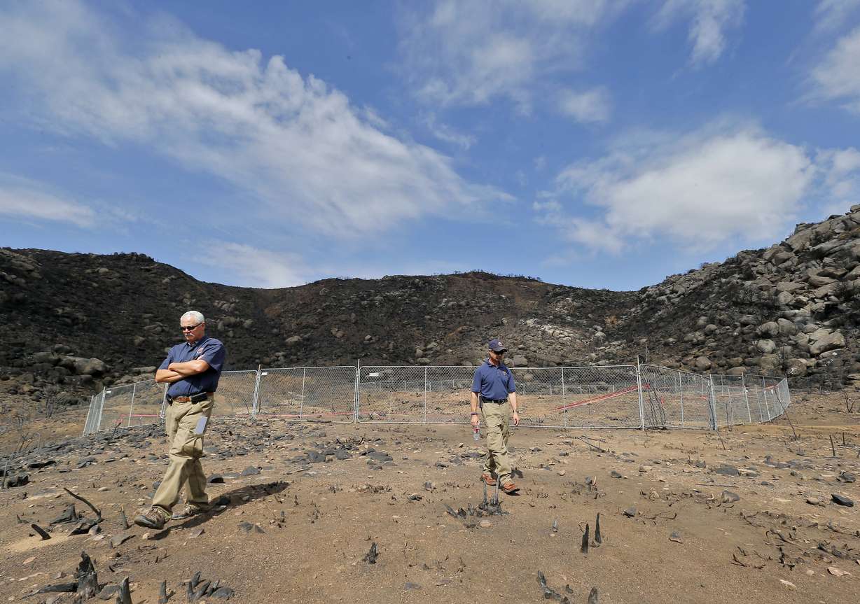Jerald Payne, left, and Kevin Boness stand at the site where 19 firefighters died battling an Arizona wildfire, July 23, 2013, in Yarnell, Ariz. As the fire grew out of control, the firefighters quickly worked to clear the area of scrub and brush hoping to endure the intense heat in their emergency shelters.