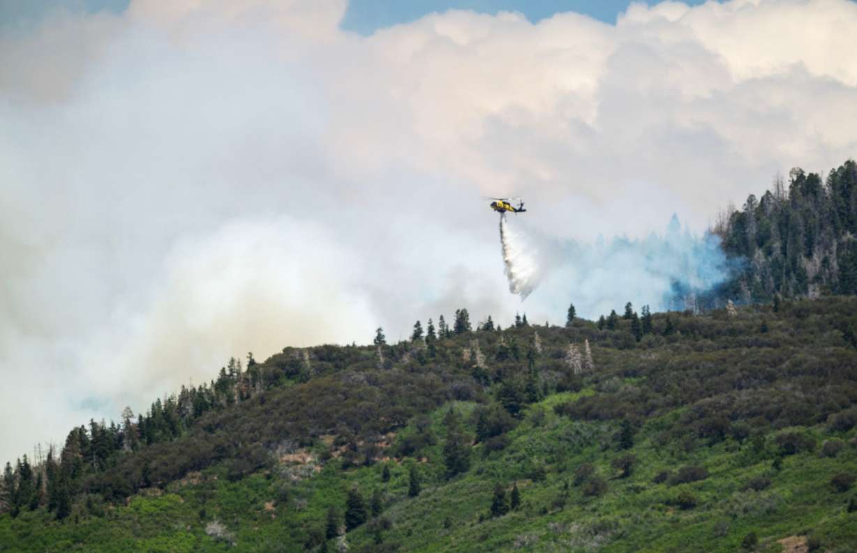 A helicopter drops water on the Cottonwood Fire that continues to burn east of the town of Beaver on Tuesday. The fire has torched more than 150 structures so far.