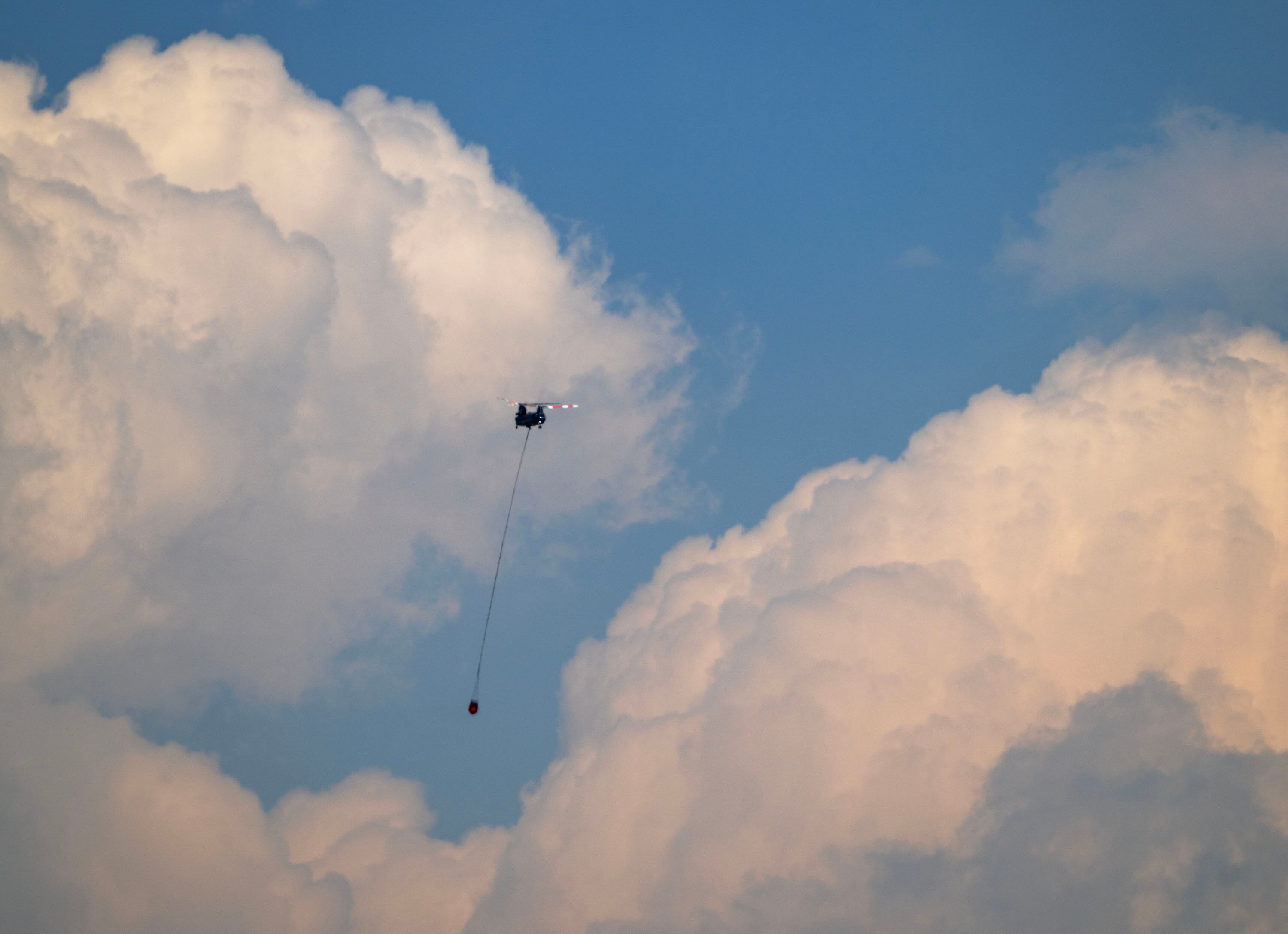 A twin rotor helicopter flies over the fire headed for water on Tuesday. The Cottonwood Fire continues to burn east of the town of Beaver.