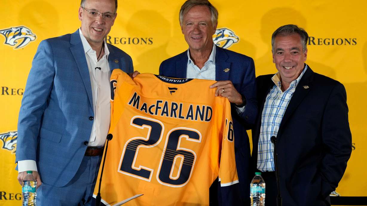 Nashville Predators new president of hockey operations and general manager Chris MacFarland, left, is presented a jersey by owner Bill Haslam, center, and CEO Sean Henry, right, during an introductory news conference at the NHL team's facility Wednesday, June 3, 2026, in Nashville, Tenn.