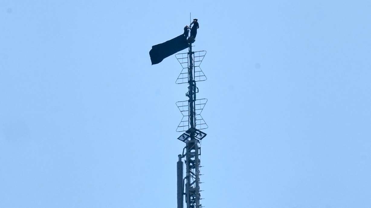 A person is shown atop the spire of the Empire State Building, in New York, Wednesday. Two people were arrested after reaching the top of the spire to unfold a banner on the "power of love."