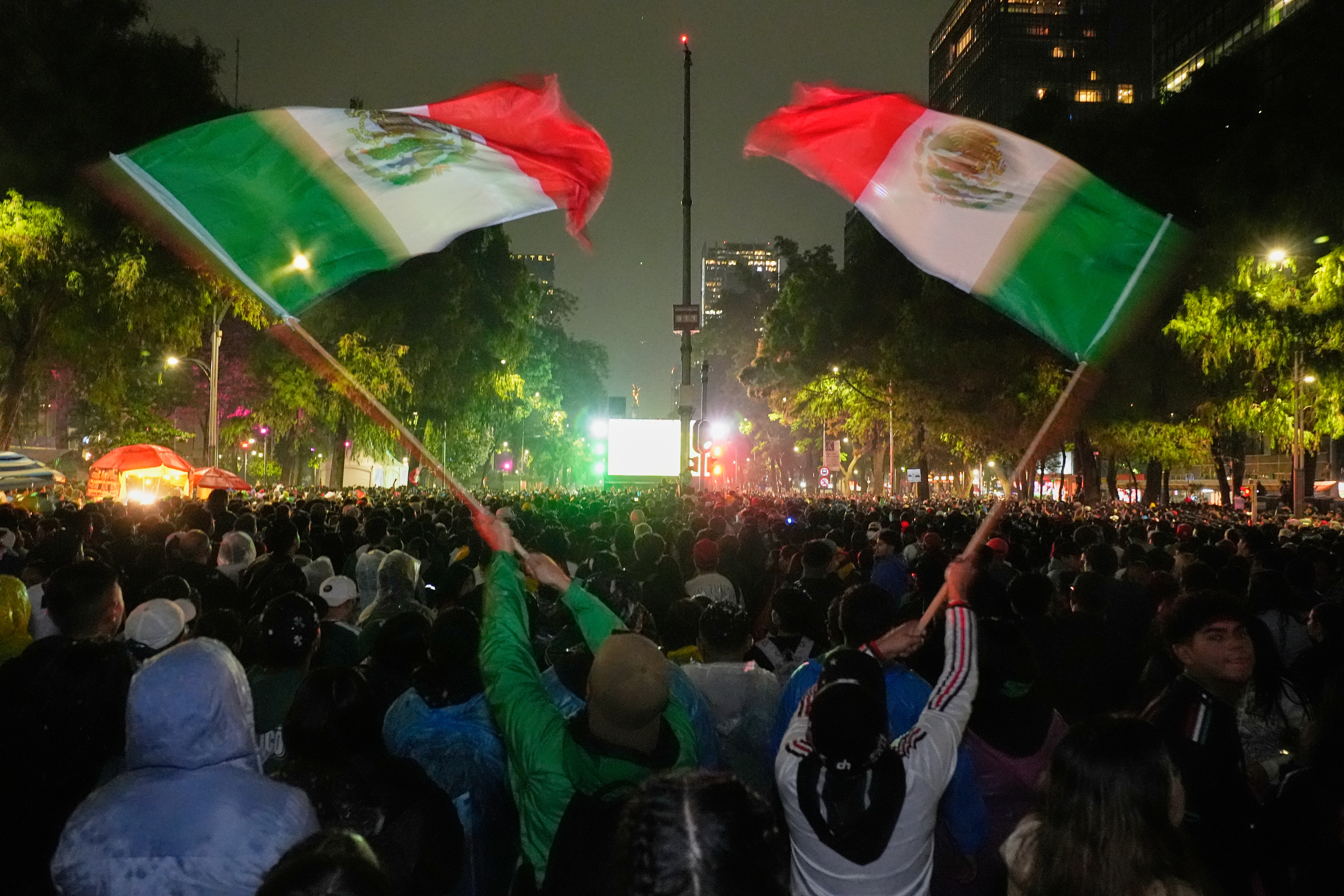 Mexican fans wave flags as they watch the World Cup round of 32 soccer match between Mexico and Ecuador near the Angel of Independence monument in Mexico City, Tuesday, June 30, 2026. 