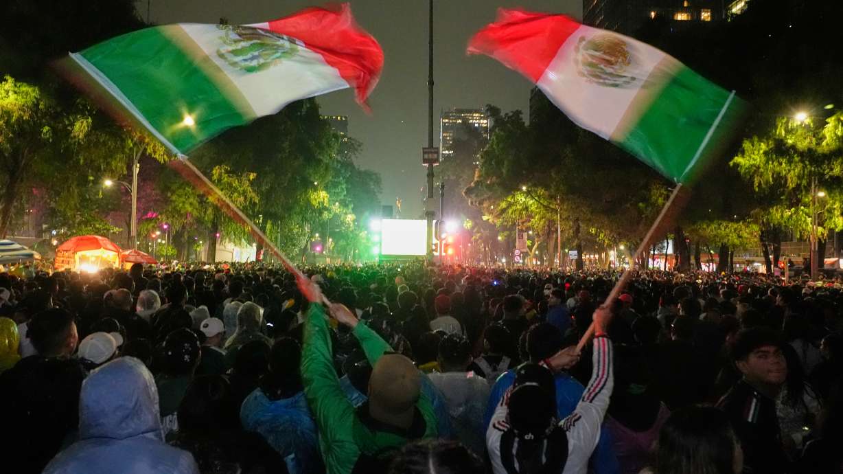 Mexican fans wave flags as they watch the World Cup round of 32 soccer match between Mexico and Ecuador near the Angel of Independence monument in Mexico City, Tuesday, June 30, 2026.
