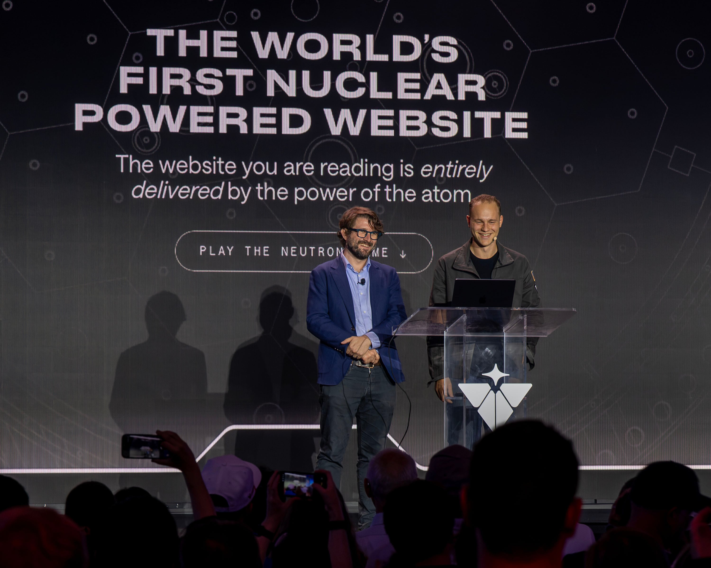 Levi Patterson, director for energy, science, and artificial intelligence infrastructure policy in the Nvidia Corporation, and Isaiah Taylor, founder and CEO of Valar Atomics, speak on stage as Valar Atomics and Nvidia celebrate a milestone in atomic energy and artificial intelligence at a large party gathering at the Orangeville site on Wednesday, July 1, 2026.