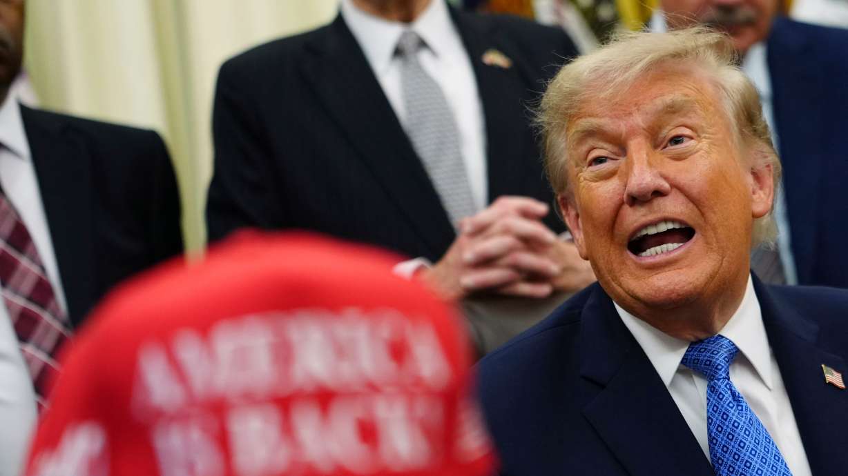 President Donald Trump speaks alongside a red cap stating, "America Is Back!" in the Oval Office of the White House, Friday, in Washington. His administration plans to launch Trump Accounts on Saturday.