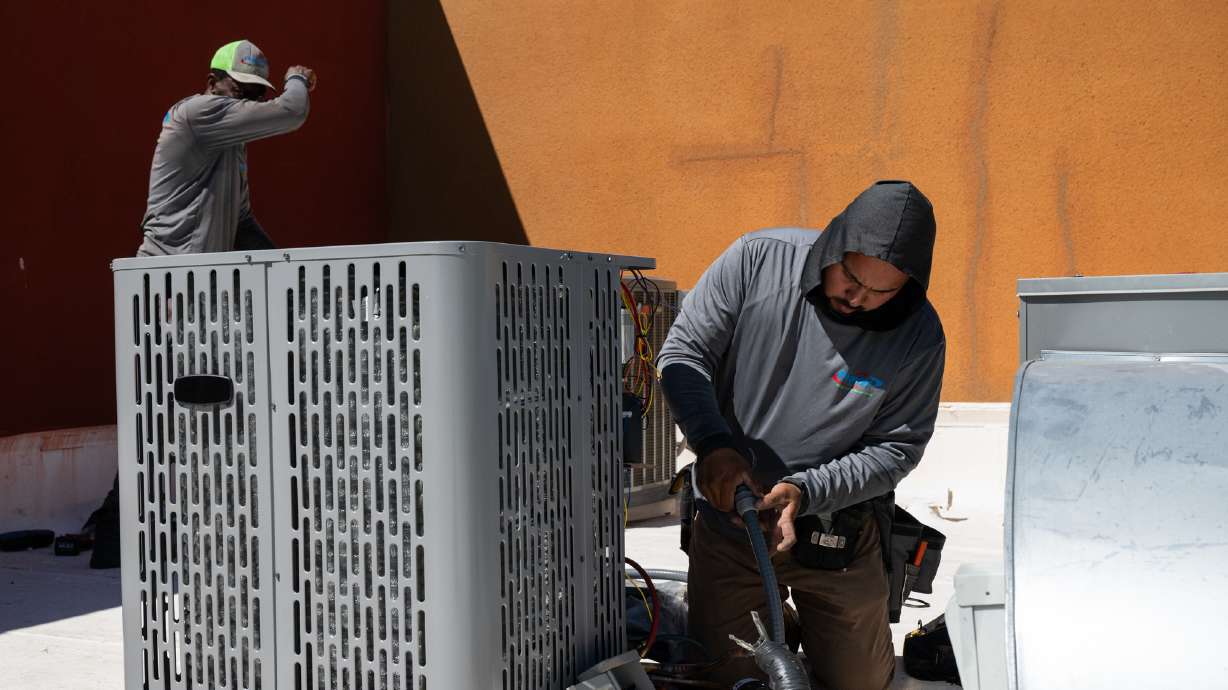 Sonel Telemaque installs a new air conditioning unit alongside Brian Hermosillo during record-breaking heat, March 19, in Tempe, Ariz. Having air conditioning is a luxury, but balancing keeping cool and saving energy and money is tricky.