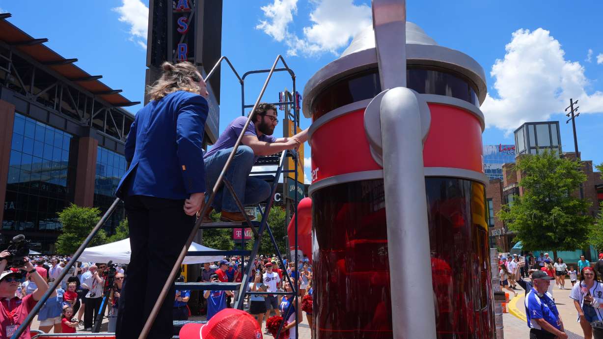 Eric Johnson and Guinness World Records adjudicator Thomas Bradford check the level of beer before certifying a world record for Largest Glass of Beer ahead of a baseball game between the Detroit Tigers and Texas Rangers, Saturday, July 4, 2026, in Arlington, Texas.