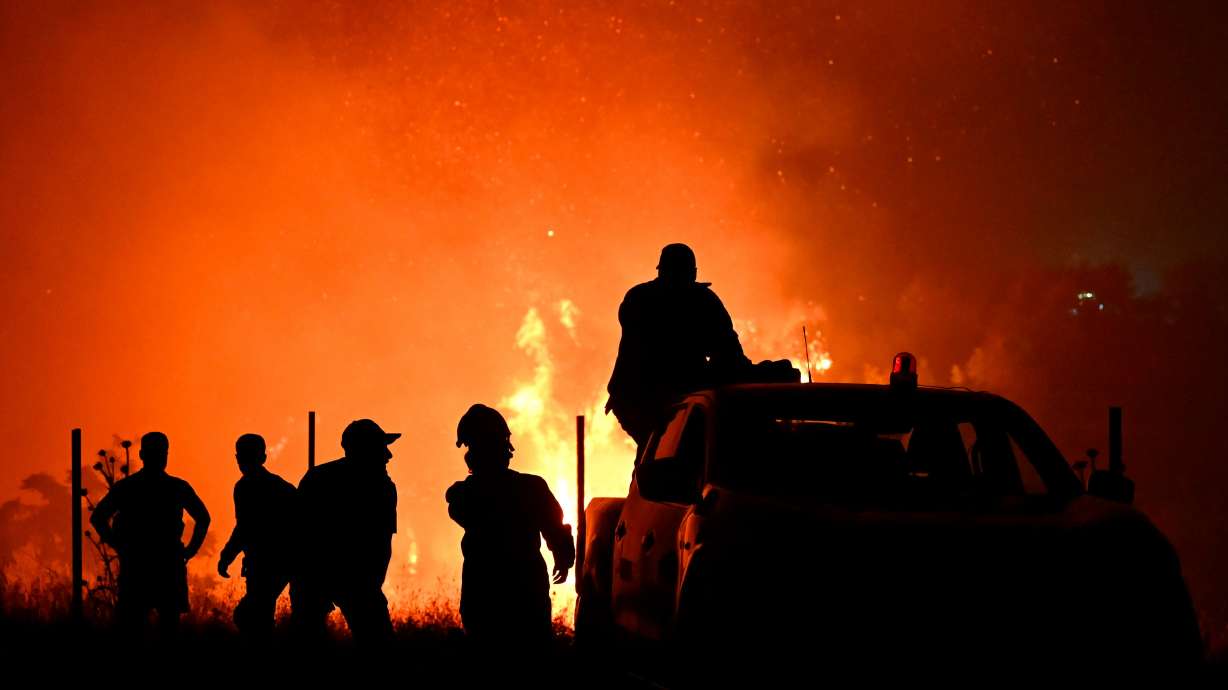 Firefighters and others are silhouetted in front of a wildfire on the outskirts of the northern city of Thessaloniki, Greece, on Saturday.