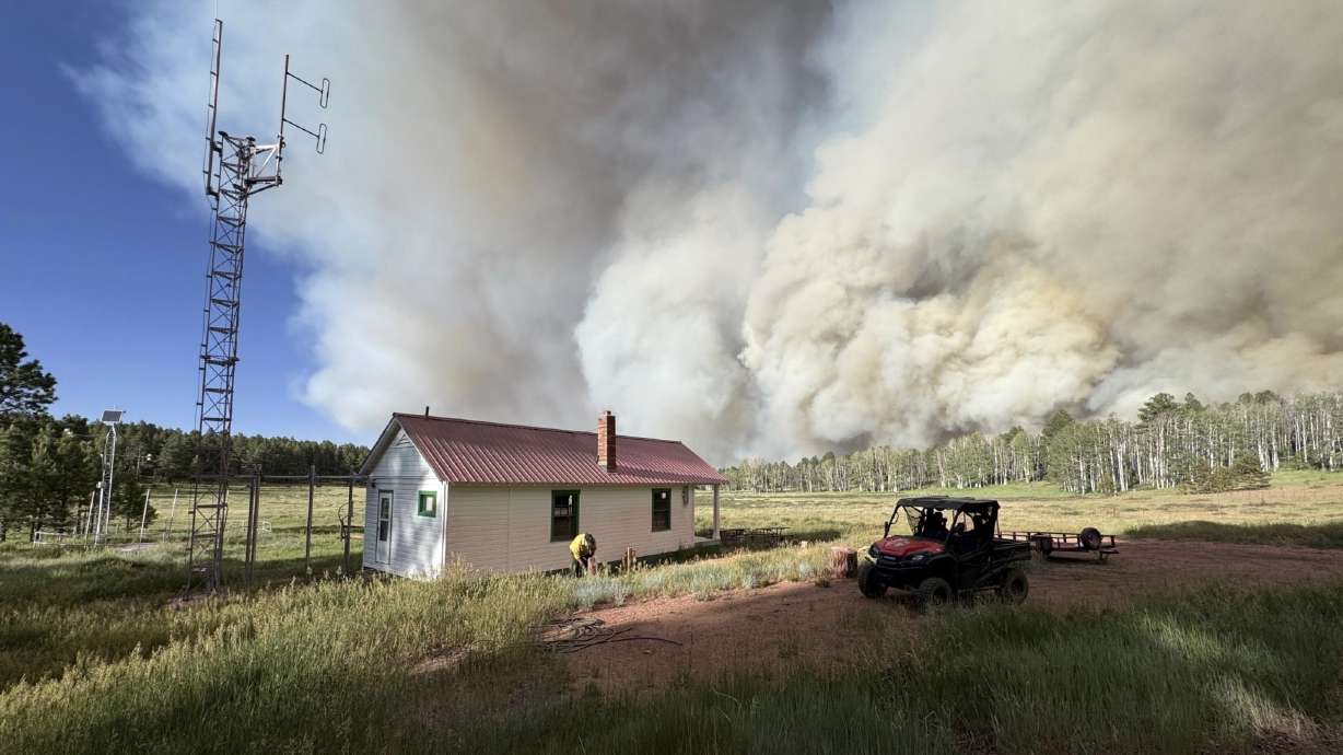 A firefighter works to protect a structure near the Babylon Fire in San Juan County on June 27. The fire has now surpassed 100,000 acres in size, officials reported on Tuesday.
