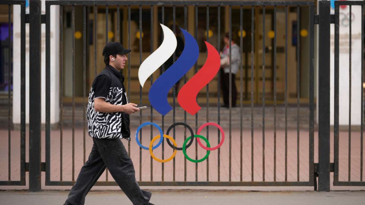 A man walks past a fence with Olympic Rings in front of the Russian National Olympic Committee building in Moscow, on Tuesday. Restrictions against Russia's participation in the Olympics have now been lifted by the International Olympic Committee.
