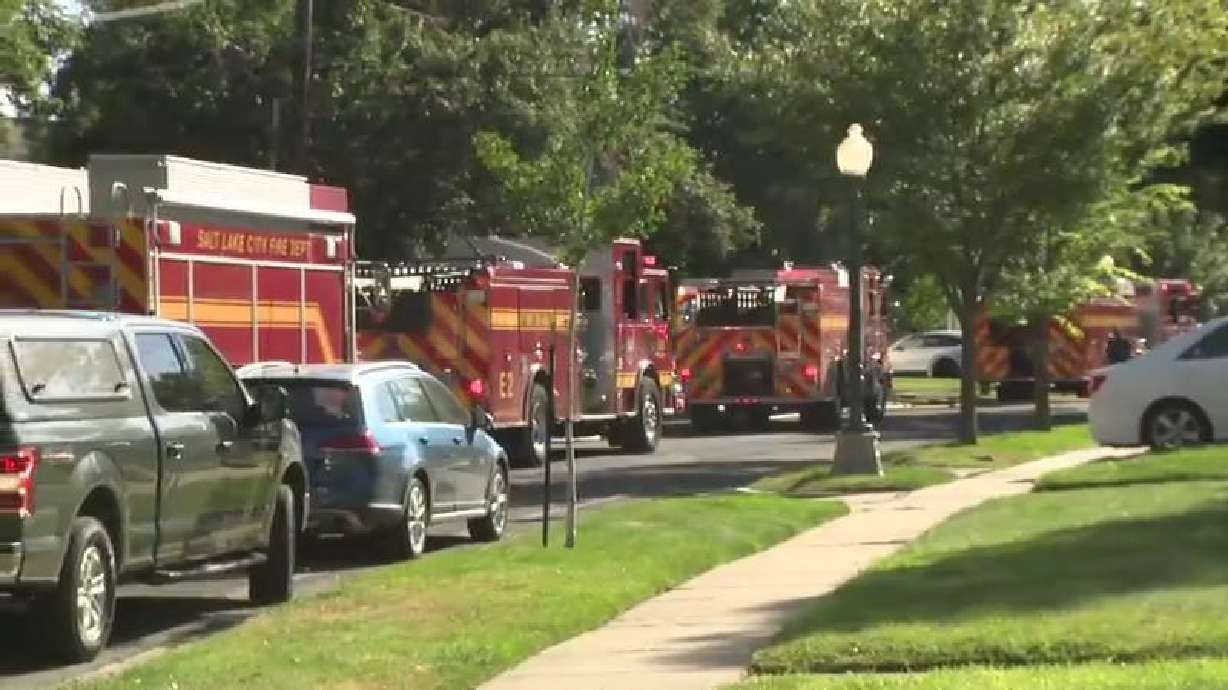 Fire trucks were positioned near the corner of Harrison Avenue and Colonial Drive in Salt Lake City as crews tackled a vegetation fire threatening structures on Wednesday.