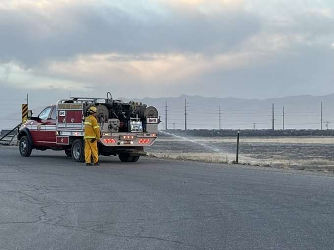 A Utah Fire Authority firefighter sprays water on a grass fire near I-80 and 7200 West on Wednesday, July 8, 2026.