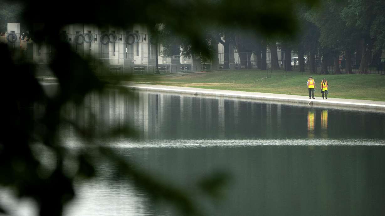 Workers pick up trash along the Lincoln Memorial Reflecting Pool, Tuesday in Washington.