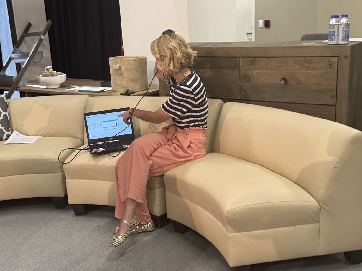 Whitney Wilkinson shows how she retrieves information from a brain implant that helps control her seizures and talks about how it has improved her quality of life at a press conference on Thursday.