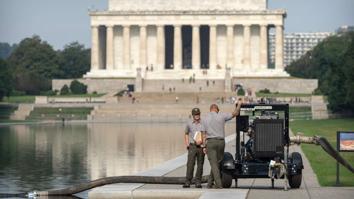 National Park Service workers stand near a pump placed next to the Lincoln Memorial Reflecting Pool, Friday, in Washington. Crews are again draining the Lincoln Memorial Reflecting Pool.