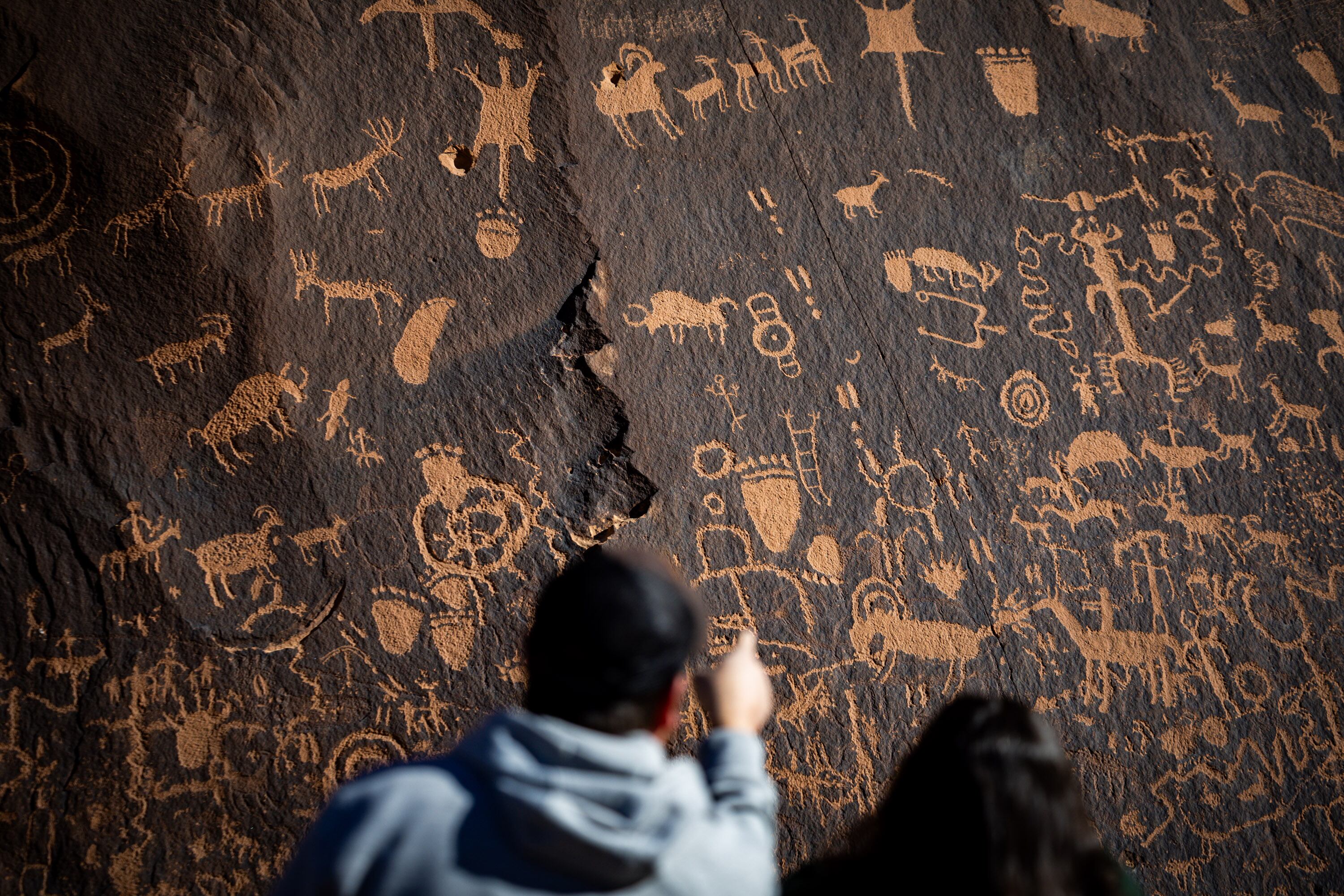 Ricky Agnew, left, and wife Christy Agnew, right, look at petroglyphs on Newspaper Rock at Bears Ears National Monument on Dec. 1, 2025. The petroglyphs on Newspaper Rock date back to 1,500 years ago. The older art is attributed to the Basketmaker and Ancestral Puebloan people who inhabited this region from approximately 500 B.C. to 1350 A.D. The more recent petroglyphs are attributed to the Ute people who still live in the Four Corners area.