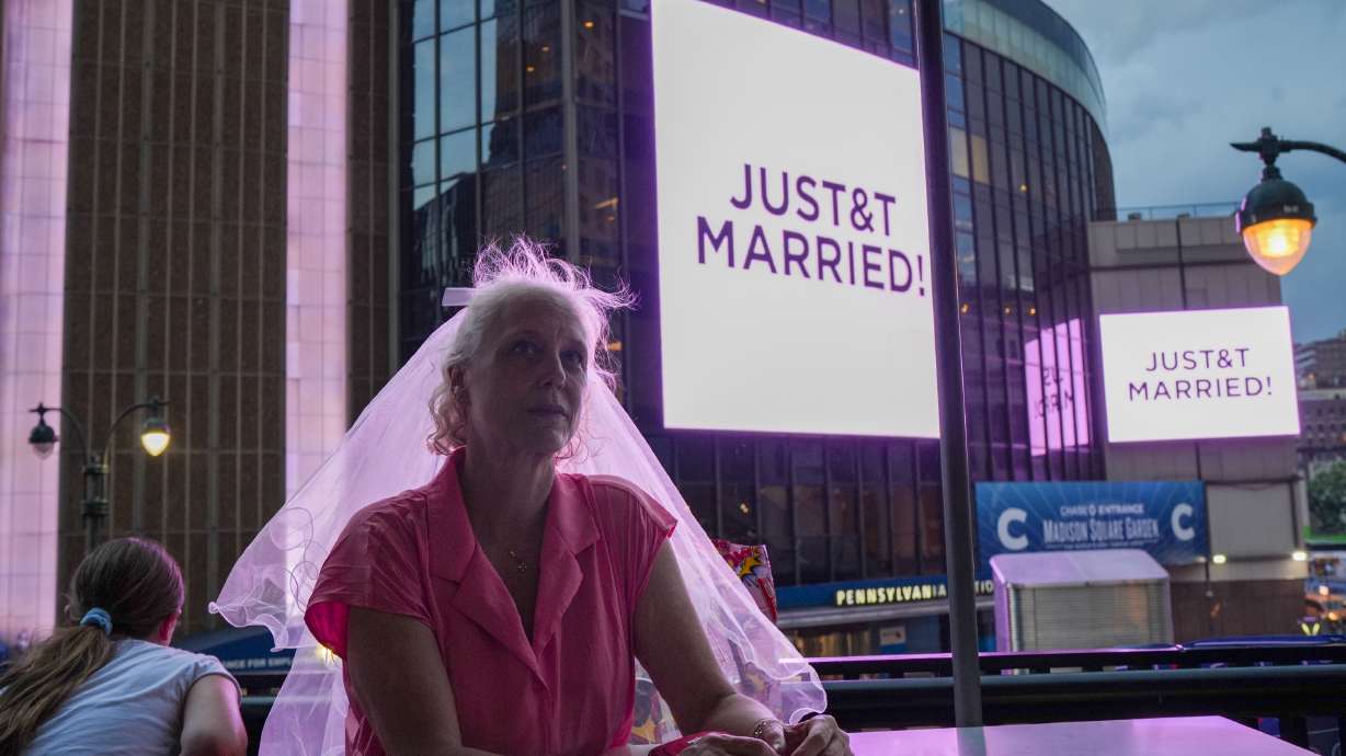 A Taylor Swift fan wearing a wedding veil sits at a restaurant next to Madison Square Garden where a "JUST&T MARRIED" sign is displayed during a wedding between singer Taylor Swift and National Football League player Travis Kelce on Friday, July 3, 2026, in New York.