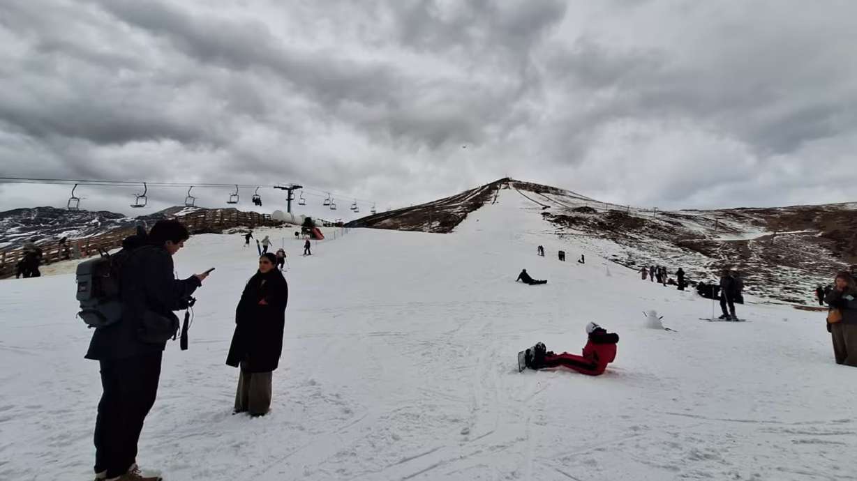 Skiers and snowboarders make use of a slope covered with artificially created snow in Santiago, Chile, on Thursday.