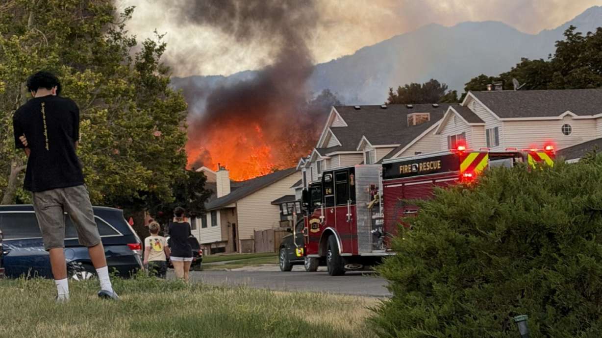 Smoke and flames are seen as crews respond to a structure fire in Millcreek on Sunday.