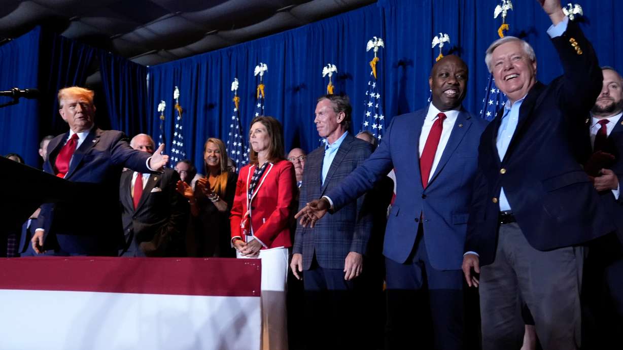 Republican presidential candidate former President Donald Trump speaks as Sen. Tim Scott, R-S.C., and Sen. Lindsey Graham, R-S.C., listen at a primary election night party at the South Carolina State Fairgrounds in Columbia, S.C., Feb. 24, 2024.