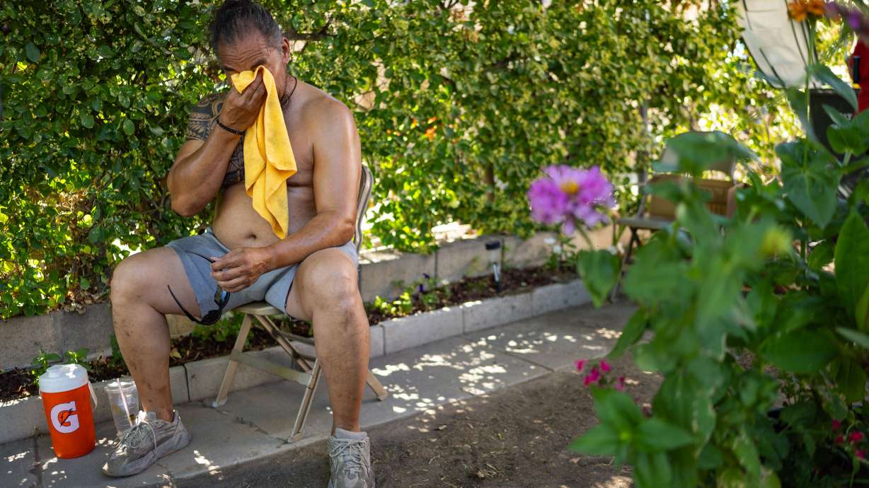 Hedley Fifita rubs his face with a towel while sitting in his front yard in the Fairpark neighborhood in Salt Lake City on Saturday. Even before this weekend's hot weather, Utah found itself on pace to have its warmest year in over a century, per federal data.