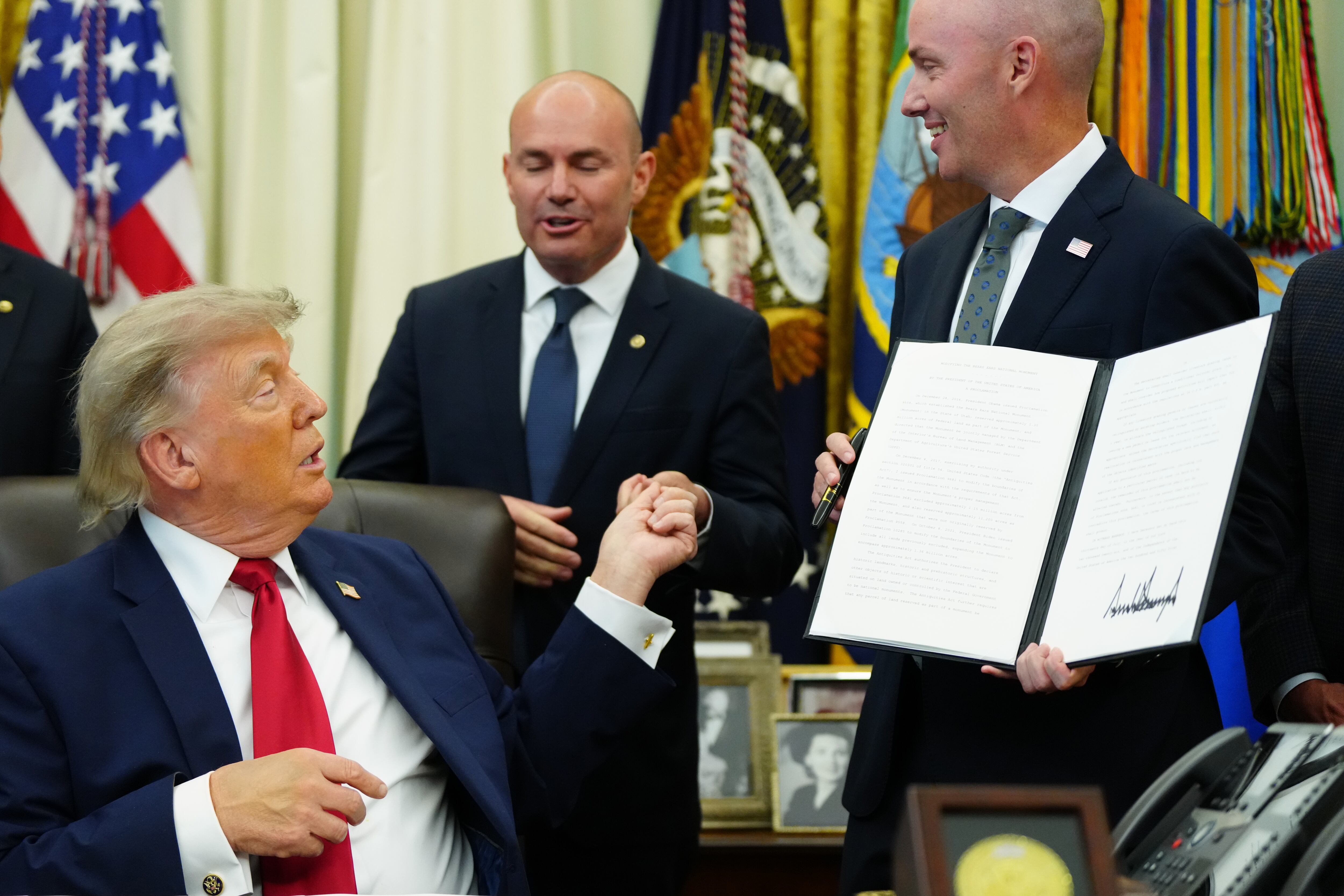 President Donald Trump hands a pen to Sen. Mike Lee as Gov. Spencer Cox watches after signing executive orders modifying the Grand Staircase-Escalante National Monument and the Bears Ears National Monument in the Oval Office of the White House, Monday in Washington. Tribal leaders said they weren't consulted before the orders were signed.