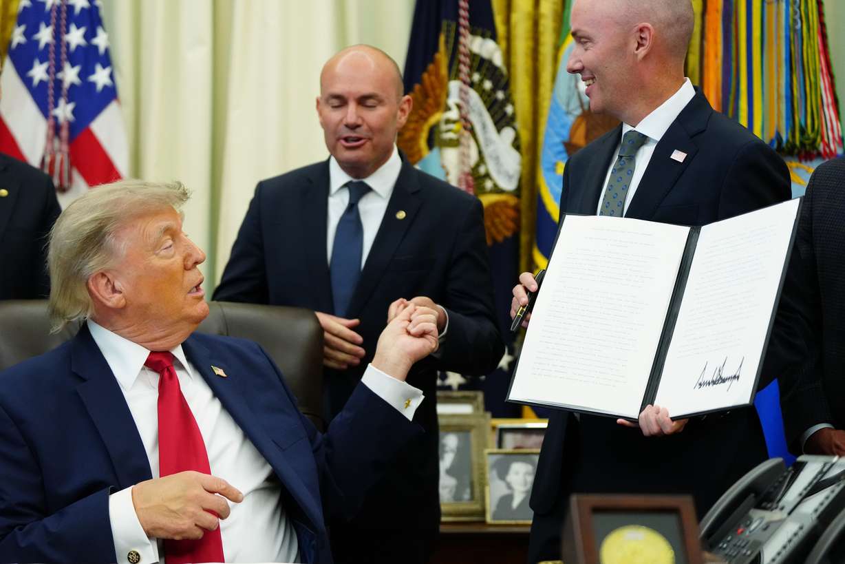 President Donald Trump hands a pen to Sen. Mike Lee as Gov. Spencer Cox watches after signing executive orders modifying the Grand Staircase-Escalante National Monument and the Bears Ears National Monument in the Oval Office of the White House, Monday in Washington. Tribal leaders said they weren't consulted before the orders were signed.