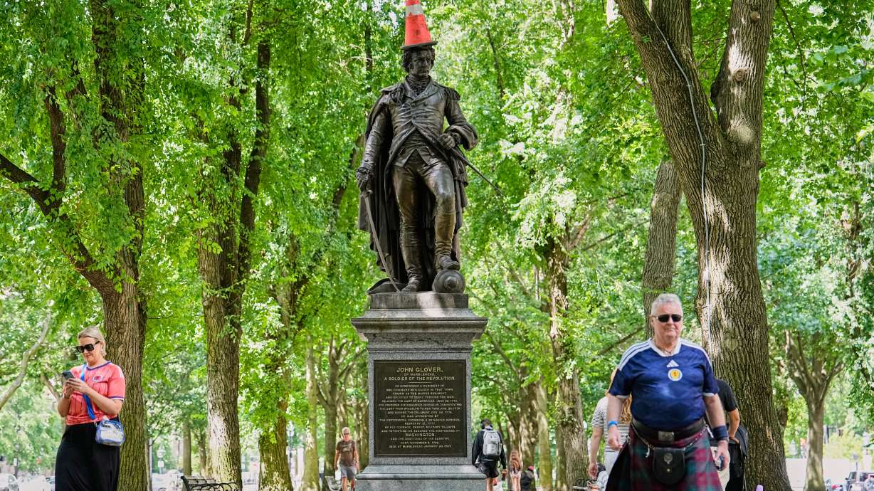 Scottish fans passing a statue of the revolutionary John Glover, humorously decorated with a traffic cone, in a park in Boston, Mass., ahead of the World Cup Group C soccer match between Scotland and Morocco, Friday, June 19, 2026.