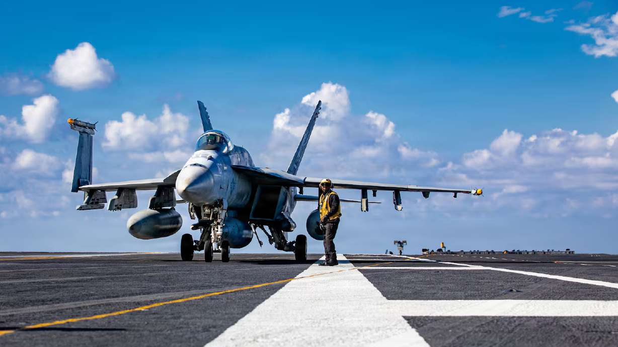 A U.S. Sailor signals to an F/A-18E Super Hornet aircraft, attached to Strike Fighter Squadron 87, on the flight deck of the world's largest aircraft carrier, USS Gerald R. Ford, while operating in support of Operation Epic Fury in the Eastern Mediterranean Sea, March 2.
