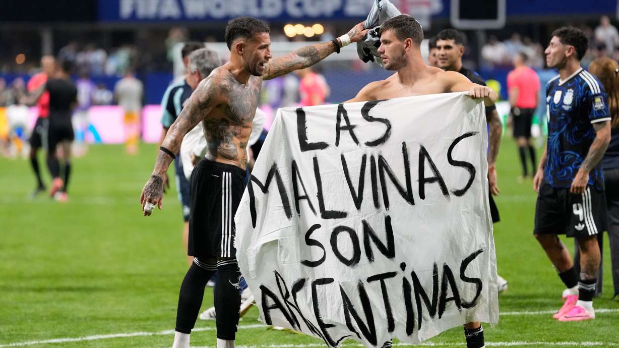 Argentina's Giovani Lo Celso holds a banner with the words "The Malvinas are Argentine", referring to the Falkland Islands, while teammate Argentina's Nicolas Otamendi gestures to him, at the end of the World Cup semifinal soccer match between England and Argentina in Atlanta, Wednesday, July 15, 2026.